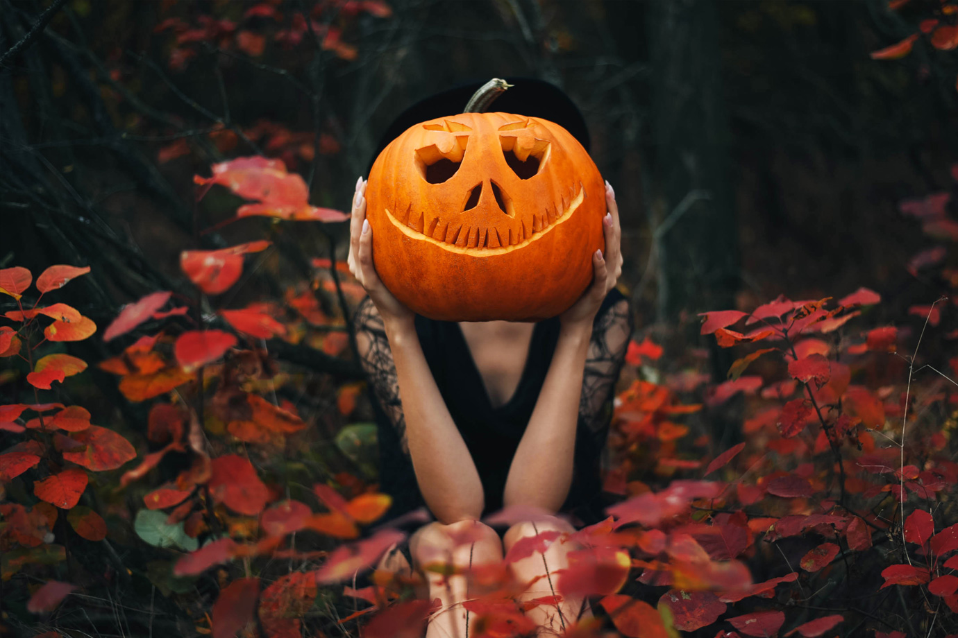 Egy lány ül az erdőben, és egy tököt tart a kezében a feje előtt