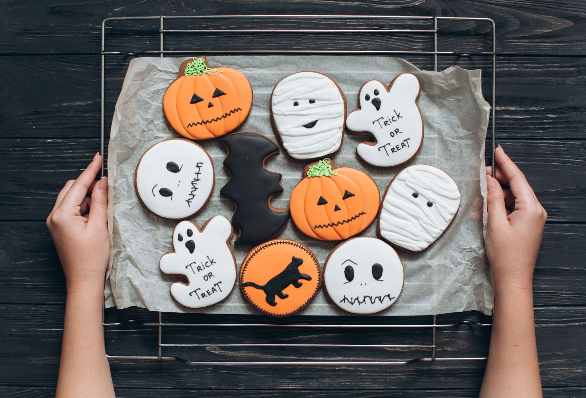 Nő halloween süteményeket - tök, szellem, koponya formájú kekszet - visz sütőlapon