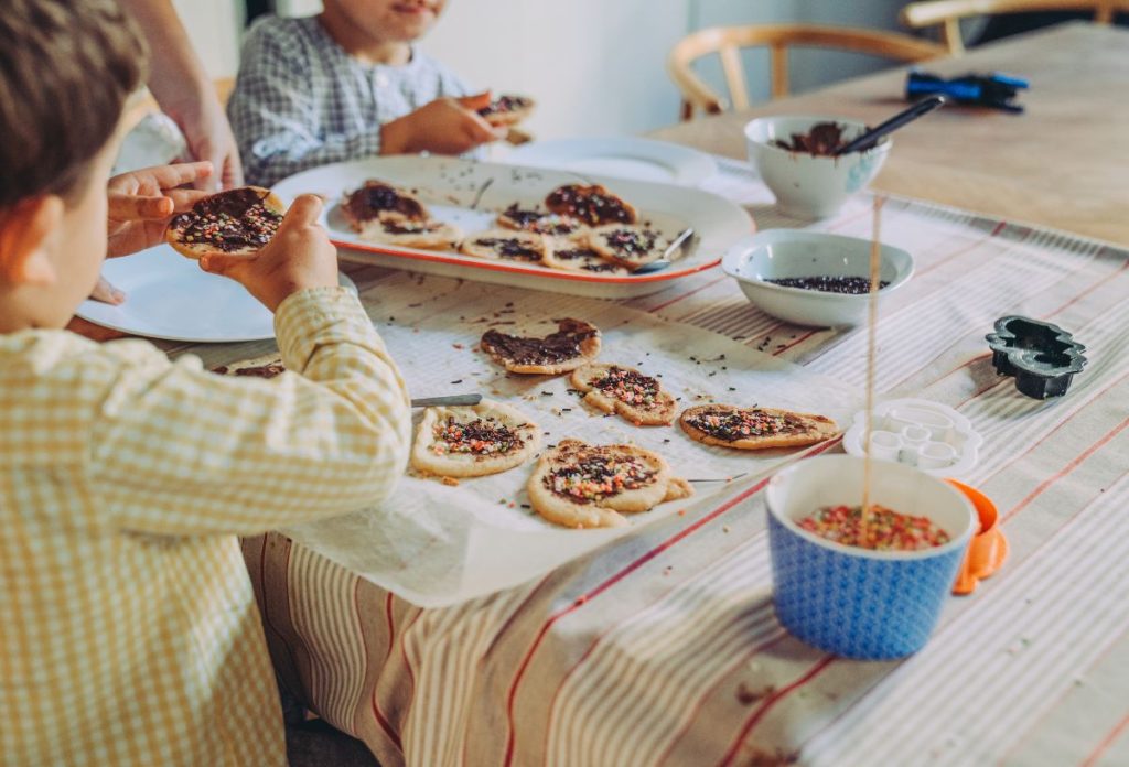 Család halloween süteményeket dekorál cukorkaszórással és csokikrémmel