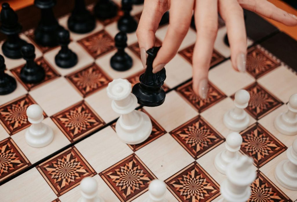 Női kéz fekete sakkfigurával üti le a fehér királynőjét
