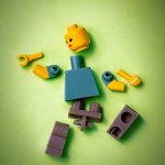 LEGO figura zöld háttérre lerakva, darabjaira szedve
