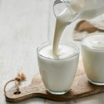 Kefírt önt kancsóból poharakba, amik egy fa deszkán állnak