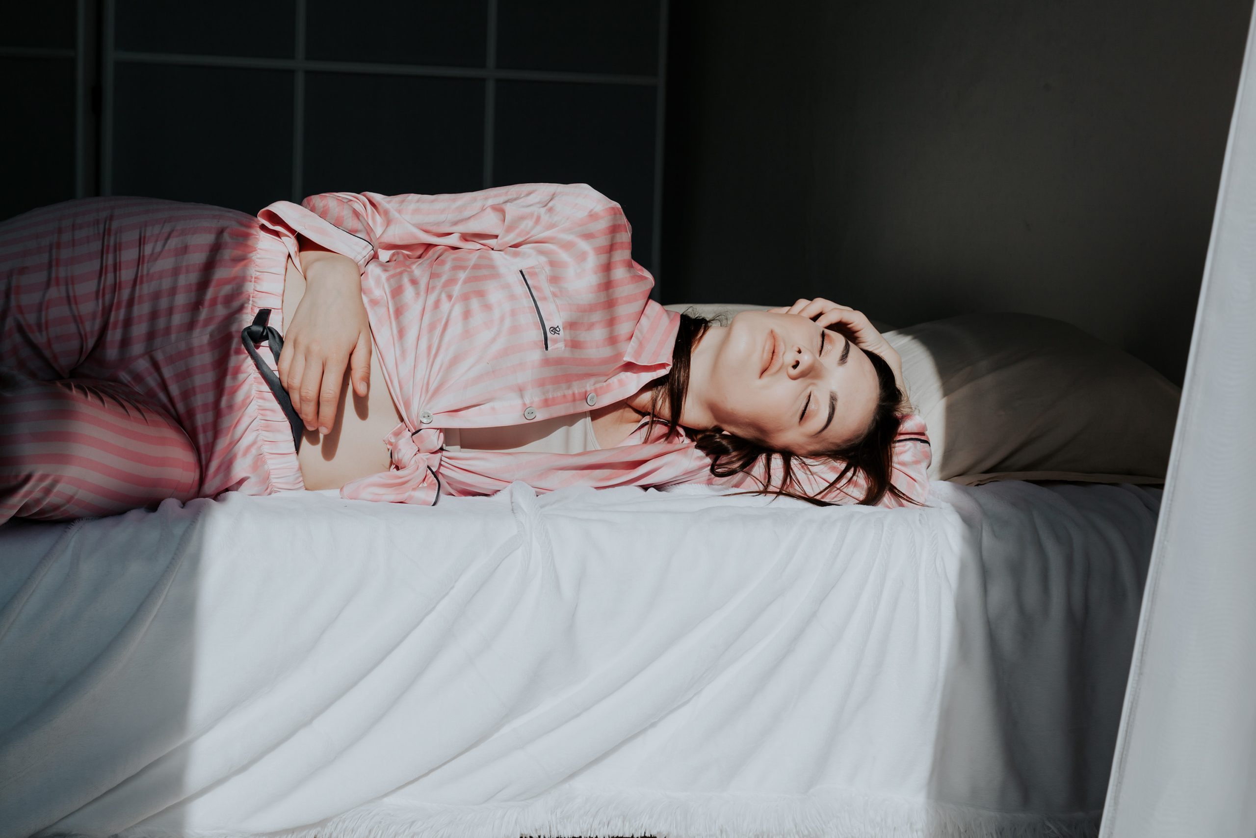 Fiatal nő rózsaszín pizsamában ébredezik