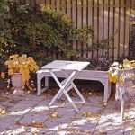 Kerti bútorok ősszel, lehullott falevelek és sárguló növények között