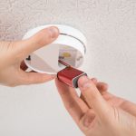 Férfi elemet cserél egy fehér szén-monoxid érzékelőben