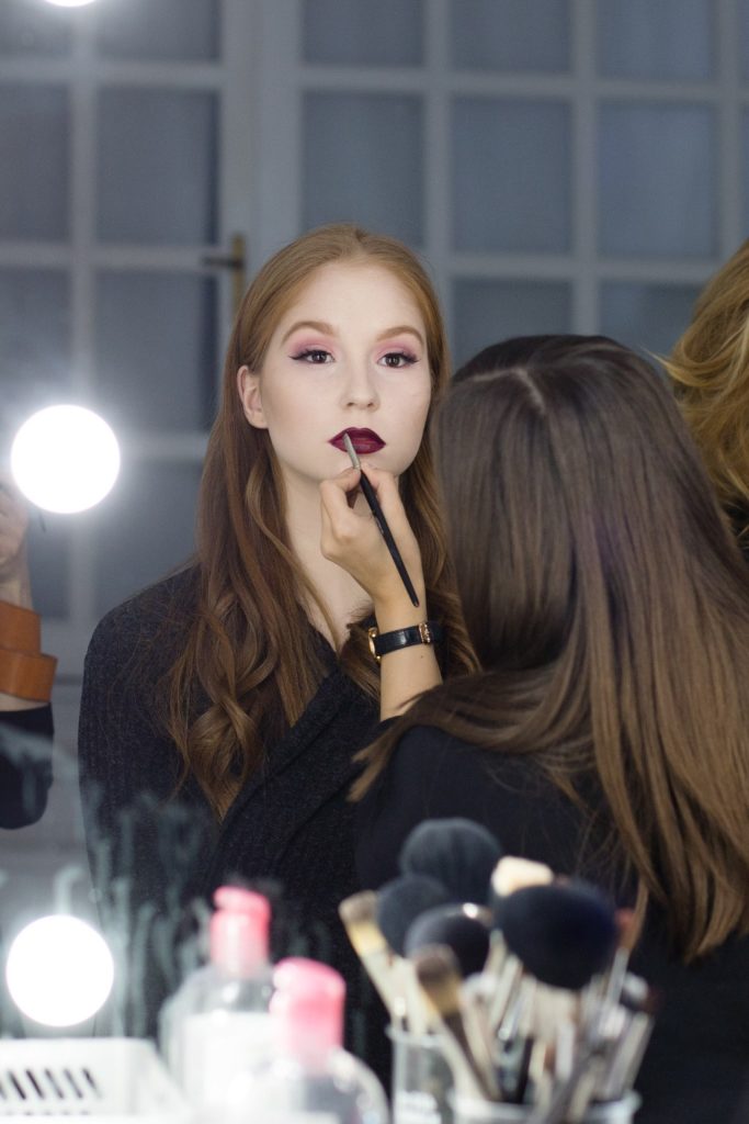 fiatal szép nőt sminkelnek erőteljes színű rúzzsal