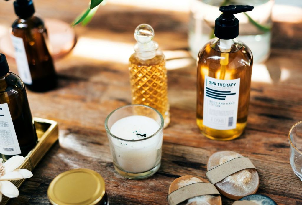 Illatgyertya, illatos olajok fa asztalon, üvegben