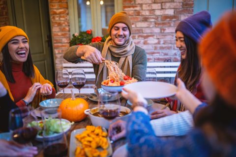 Barátok csoportja étkezik egy kerti partin télen.