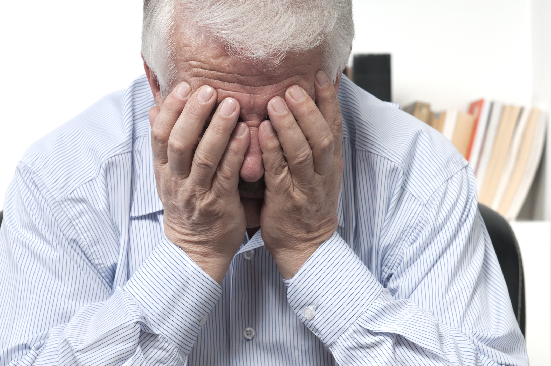 idősebb férfi az arcát fogja