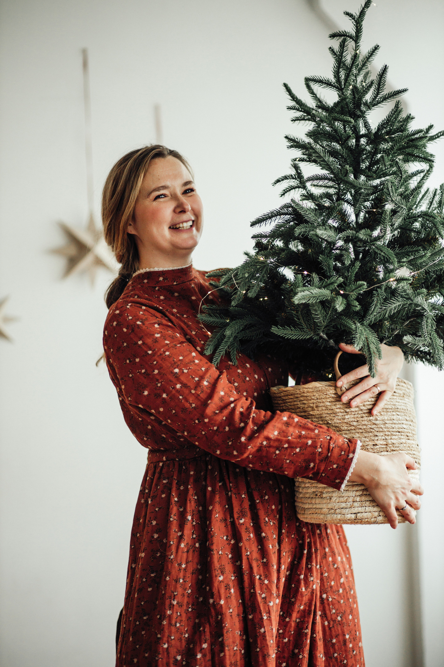 Fiatal vidám nő tart egy egy cserepes karácsonyfát a kezében