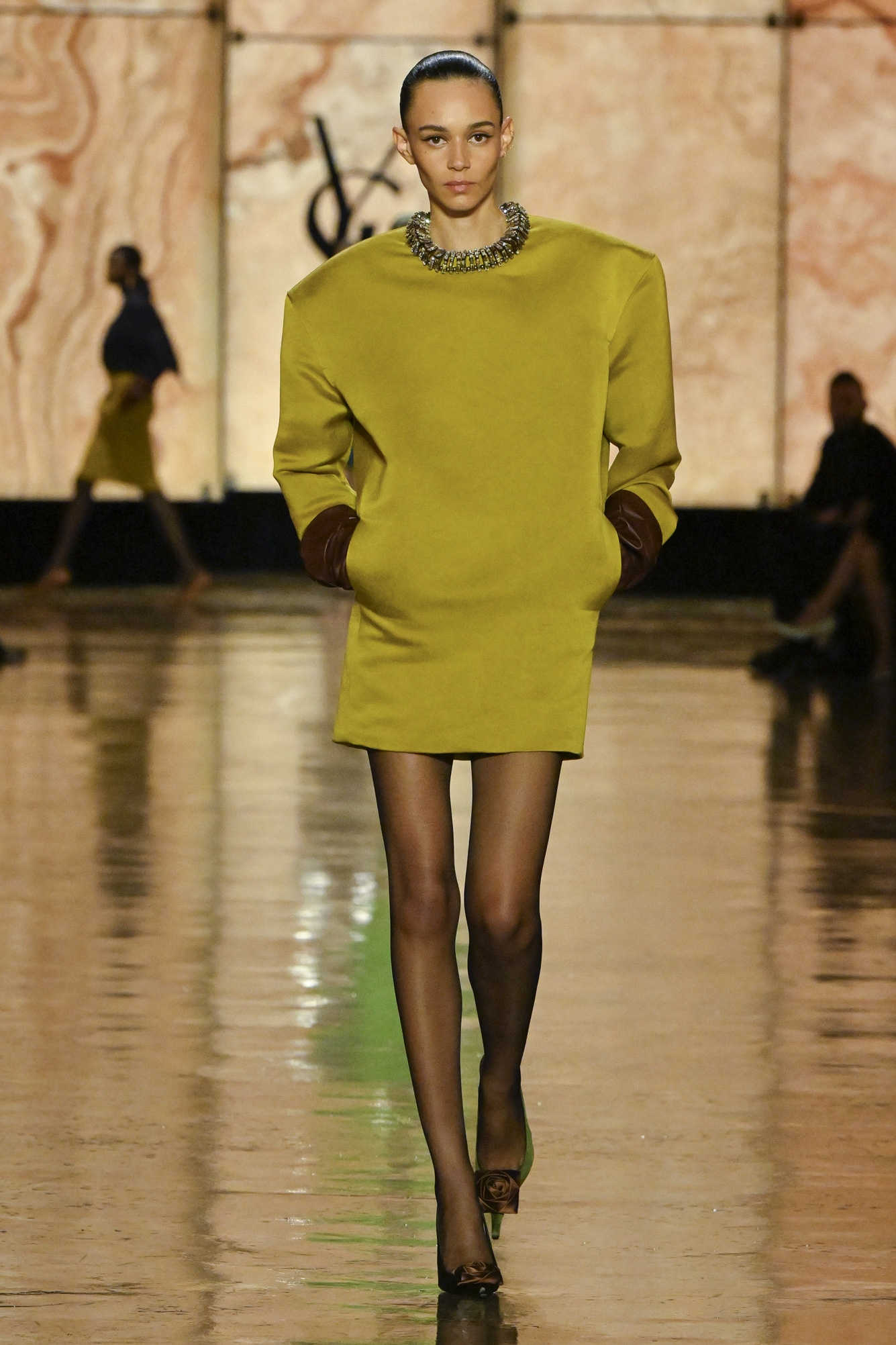 Egy modell sétál a kifutón sárgászöld miniruhában a Saint Laurent Ready to Wear őszi/téli 2025-2026 divatbemutatóján a Párizsi Divathét részeként, 2025. március 10-én, Párizsban, Franciaországban