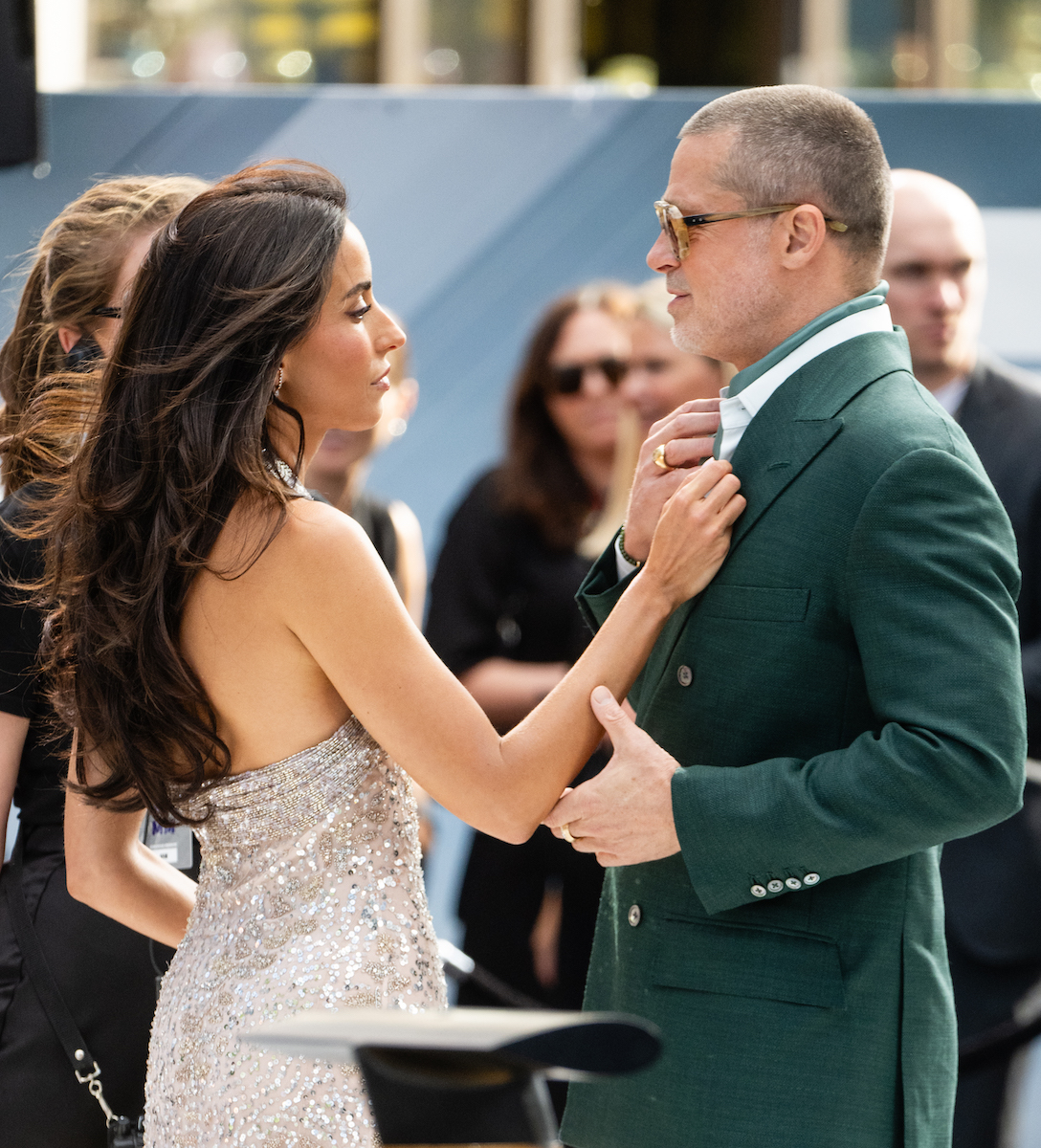 Brad Pitt zöld zakóban, napszemüvegben, Ines de Ramon a nyakkendőjét igazítja