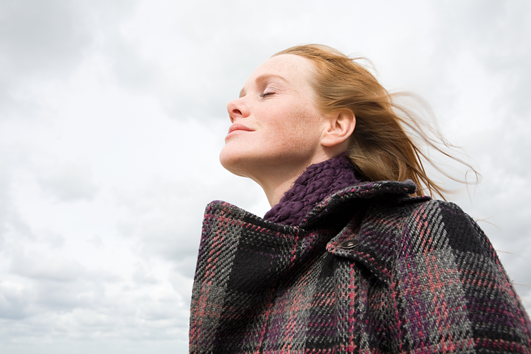 Nő behunyt szemmel mosolyog