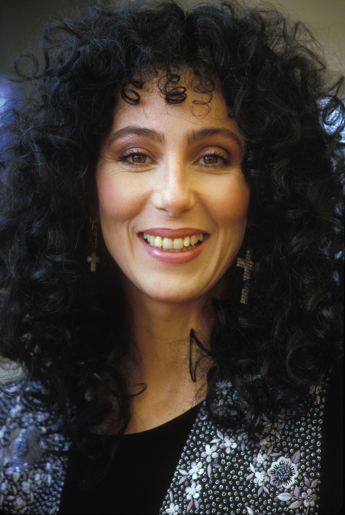 Cher boldogan mosolyog, nagy fekete göndör fürtökkel