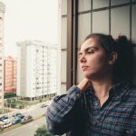 Nő ül az ablakban, szomorúan néz kifelé