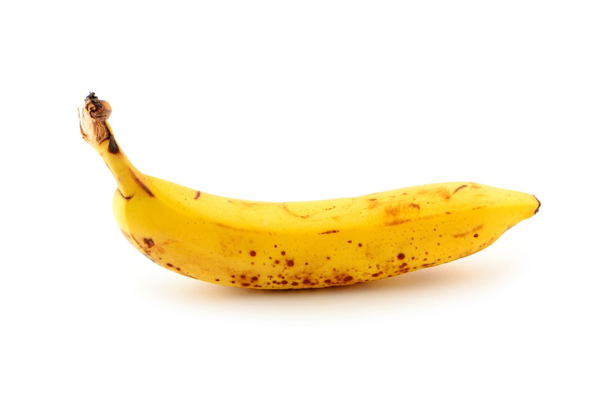 Egy darab érett, barna foltos banán fehér háttéren