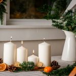 Hosszúkás tálon négy fehér gyertya, körülötte szárított narancs, toboz, fenyő