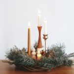 Fenyőágak között négy különböző gyertyából álló adventi koszorú