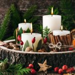 Modern, természeti elemeket, terméseket, bogyókat, fahéjat, apró ágakat tartalmazó adventi koszorú, fehér, vastag gyertyákkal