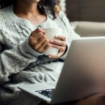 Nő ül ölében nyitott laptoppal