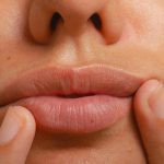 Női száj közelről, ujjakkal