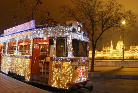 A budapesti 19-es villamos fényfüzérekkel díszítve, háttérben a Parlament épülete