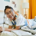 Ázsiai nő mosolyogva fekszik az ágyon