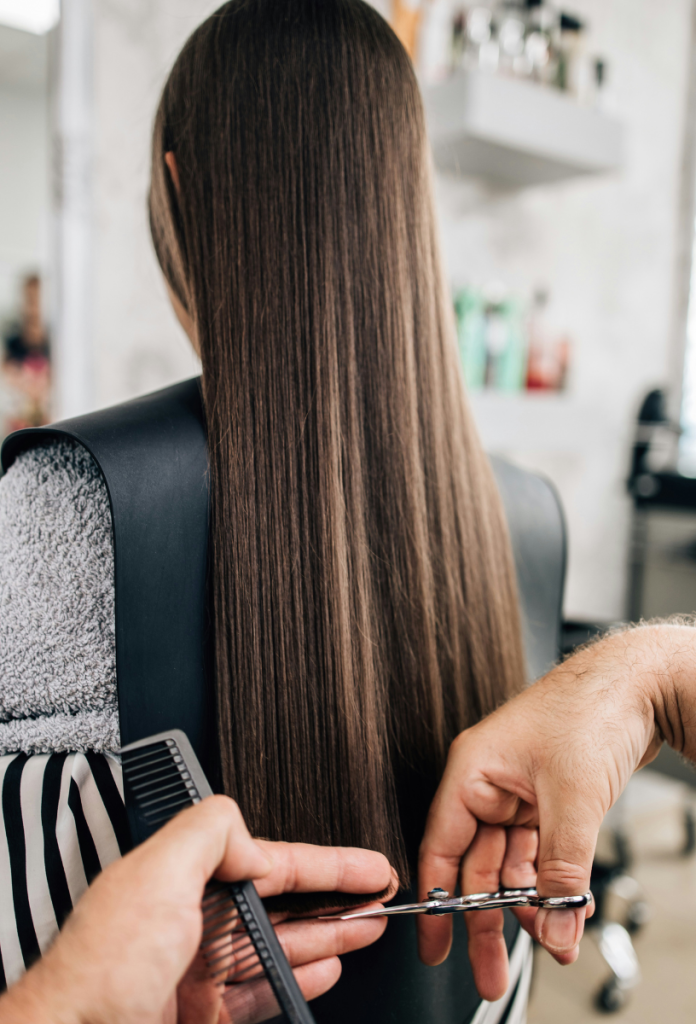 Extra hosszú barna hajú nő hajvégeit frissíti a fodrász