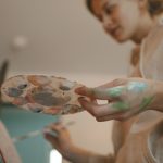 Nőnek festékes a keze, éppen fest egy képet