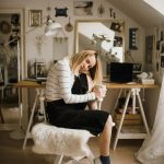 Egy szőke hajú nő ül egy széken felhúzott lábbal