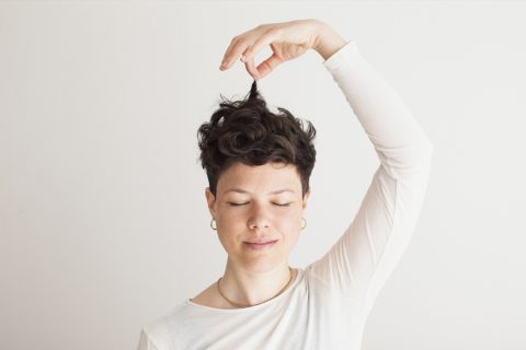 Egy boldog középkorú felnőtt nő csukott szemmel tartja a rövid haját