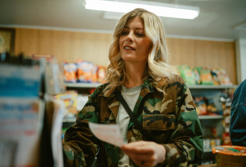 Fiatal szőke nő lottószelvényt vásárol