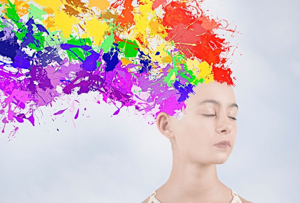Fehér bőrű nő csukott szemmel, szivárványszínű festék a haja helyén