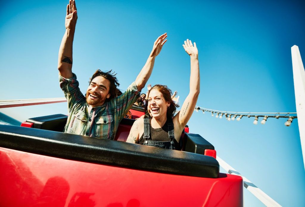 Fiatal pár hullámvasúton feltartott kézzel nevet