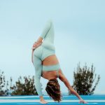 rugalmasság: nő fejjel lefelé pózban jógázik menta színű jógaruhában