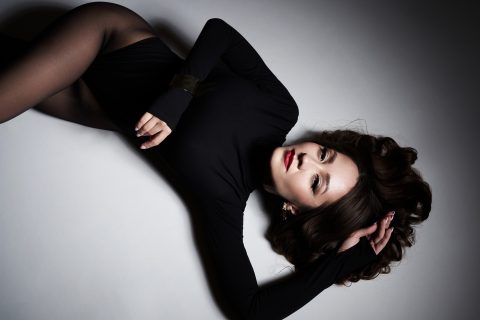 Modell fekete harisnyában fekszik a padlón