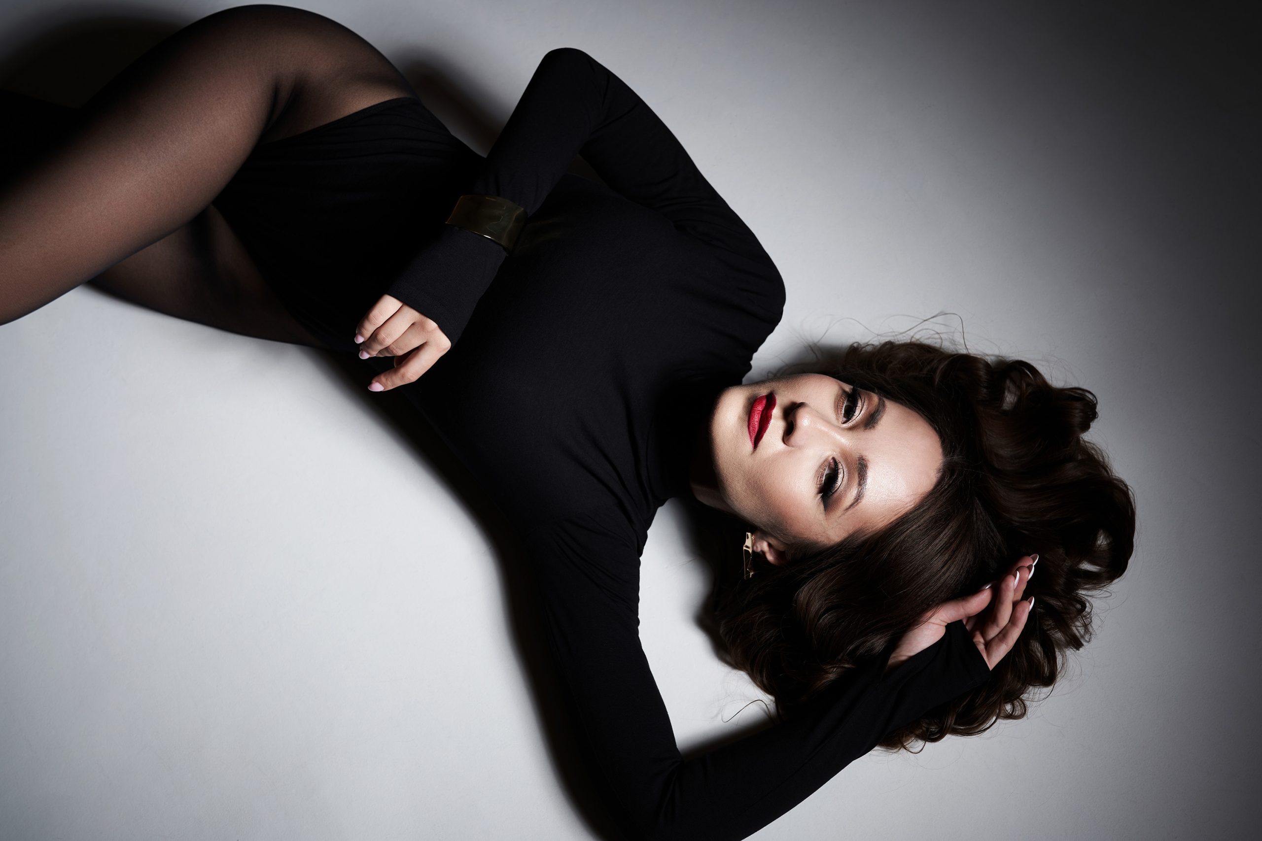 Modell fekete harisnyában fekszik a padlón