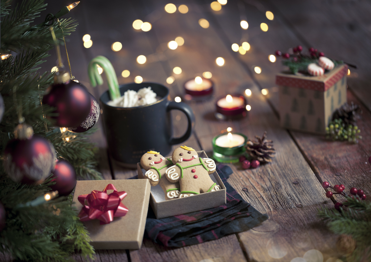 Karácsonyi mézeskalács-emberkék és forró csokoládé fa felületen.