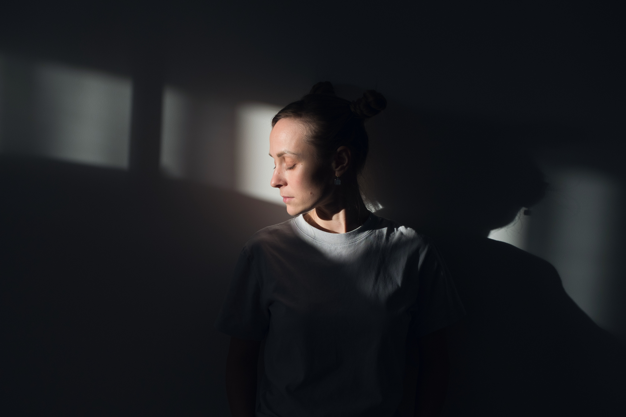 Nő a sötétben áll, falnak dőlve