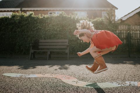 Kislány ugrik a szabadban egy játszótéren