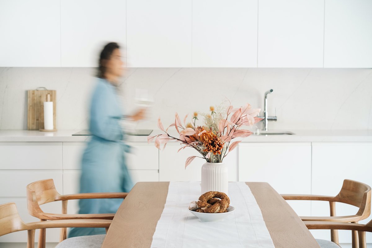 Elmosódott alak egy gardróbon keresztül sétál át a konyhán. Modern, minimalista enteriőr.