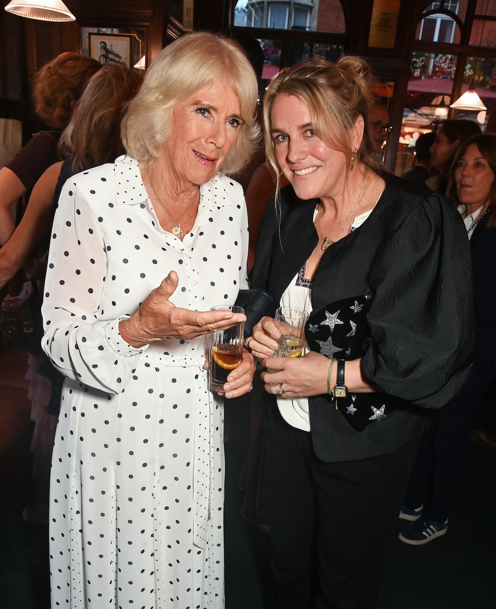 kamilla-kiralyne-gyerekei-kihagyjak-a-karacsonyt-a-palotaban | Marie Claire Kamilla királyné pöttyös fehér ruhában lánya, Laura Lopes társaságában Tom Parker Bowles Cooking The Crown című könyvének bemutatóján 2024-ben.