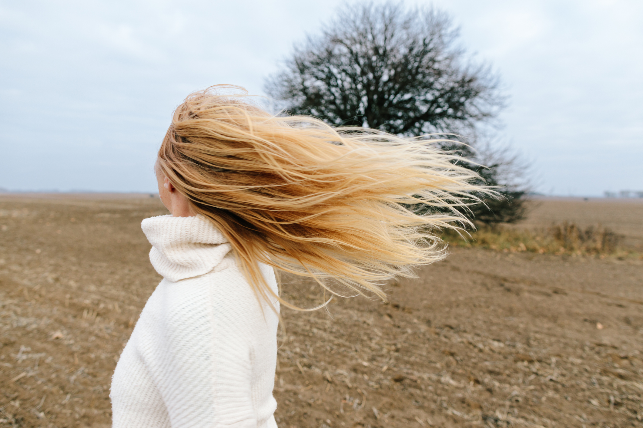 Szép szőke hajú nő lobogtatja a haját a pusztában