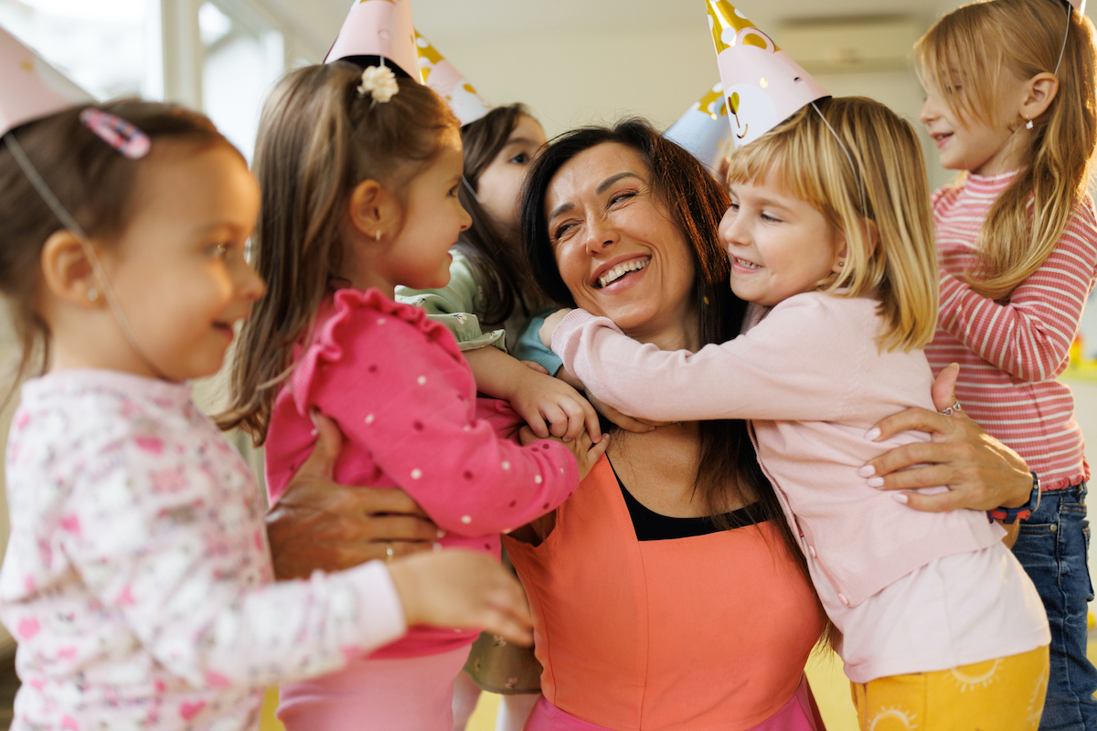 Gyerekek megölelnek egy mosolygó felnőtt nőt
