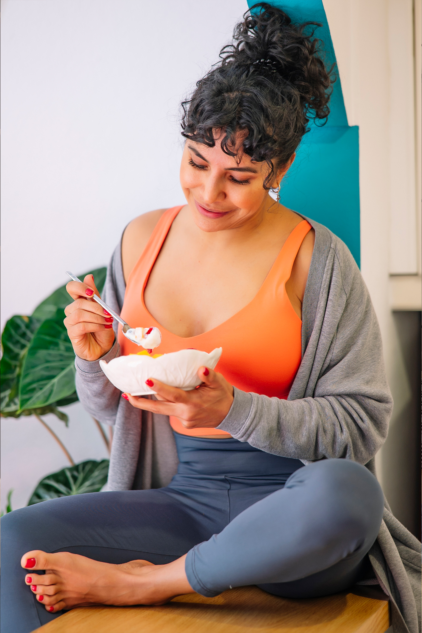 Egy boldogan mosolygó nő egészséges reggelit eszik friss gyümölcsökkel egy modern konyhában