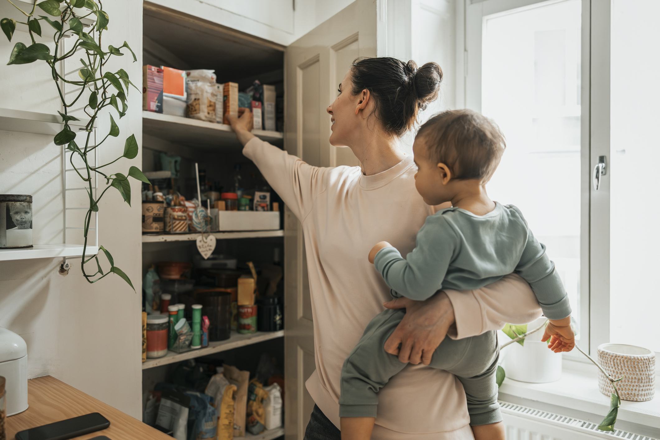 Nő kisgyerekkel a karján rendezi a kamrát