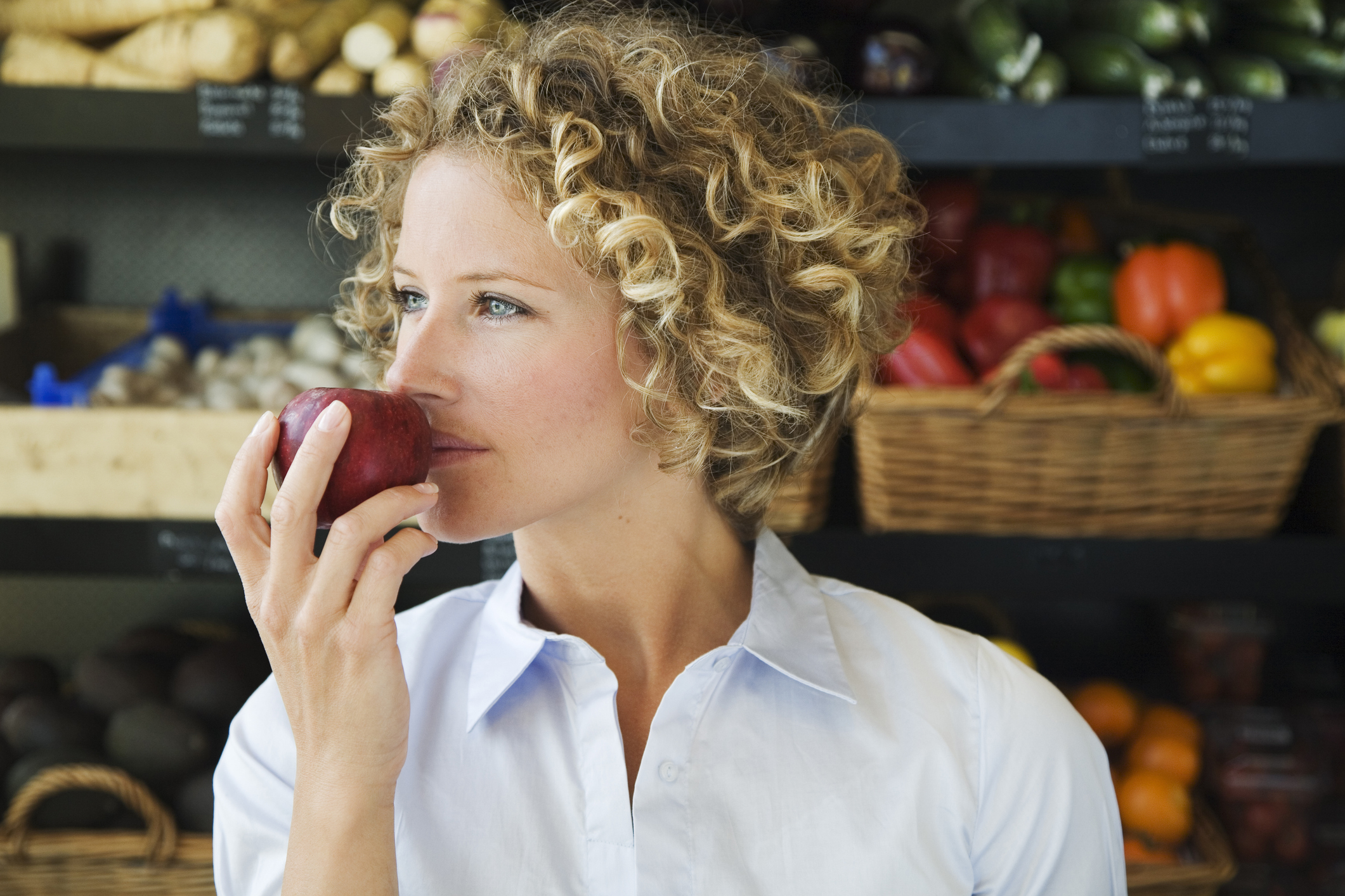 Szőke nő egy almát tart a szájához