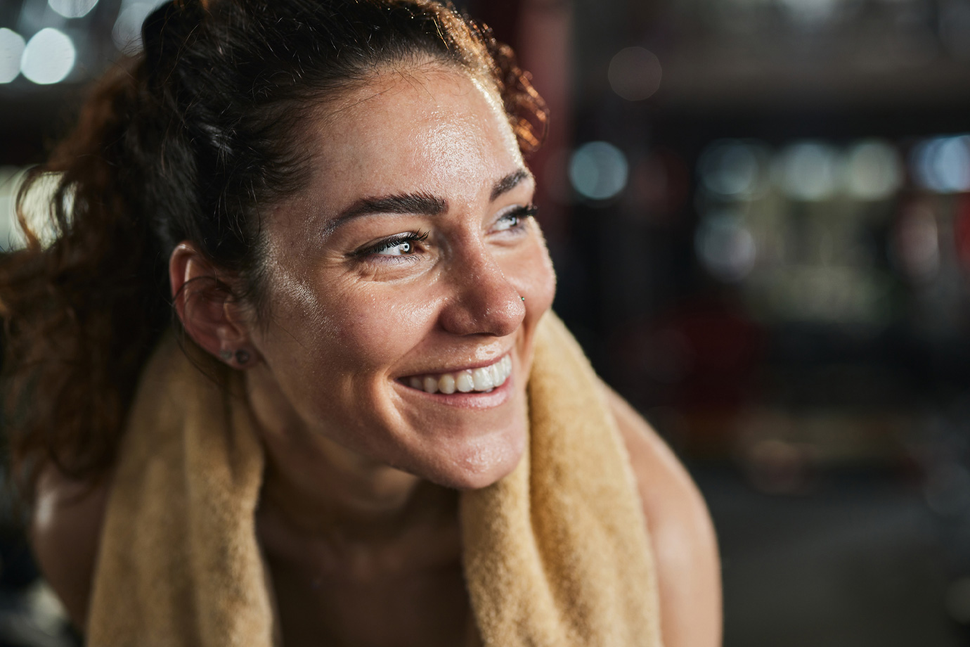 Boldog női sportoló törölközővel edzés után az edzőteremben.