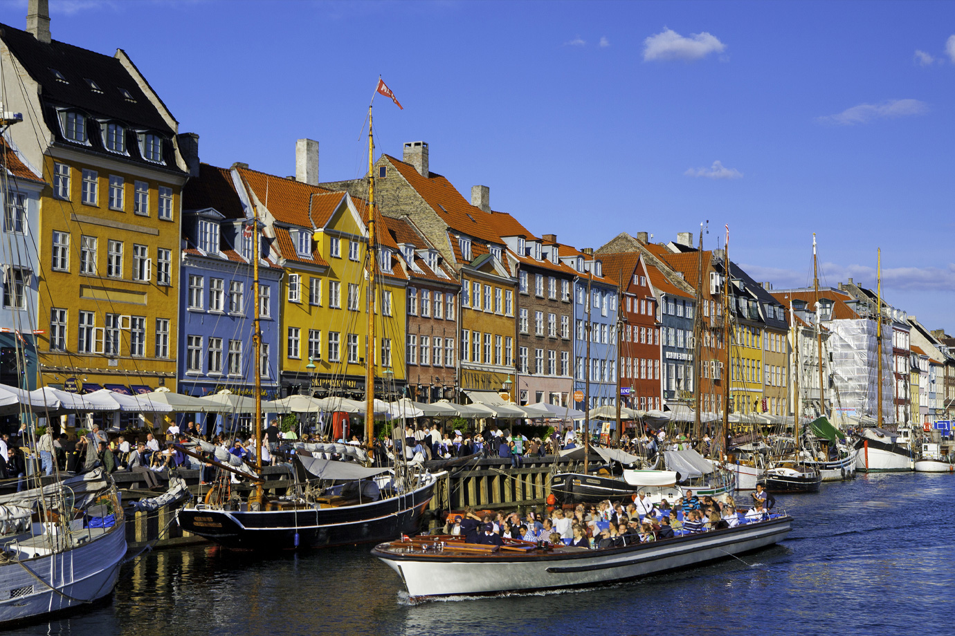 Dánia, Koppenhága. Hajók és emberek a kikötőben, a háttérben színes házak.