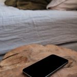 Egy telefon az ágy mellett egy fatönk éjjeli szekrényen